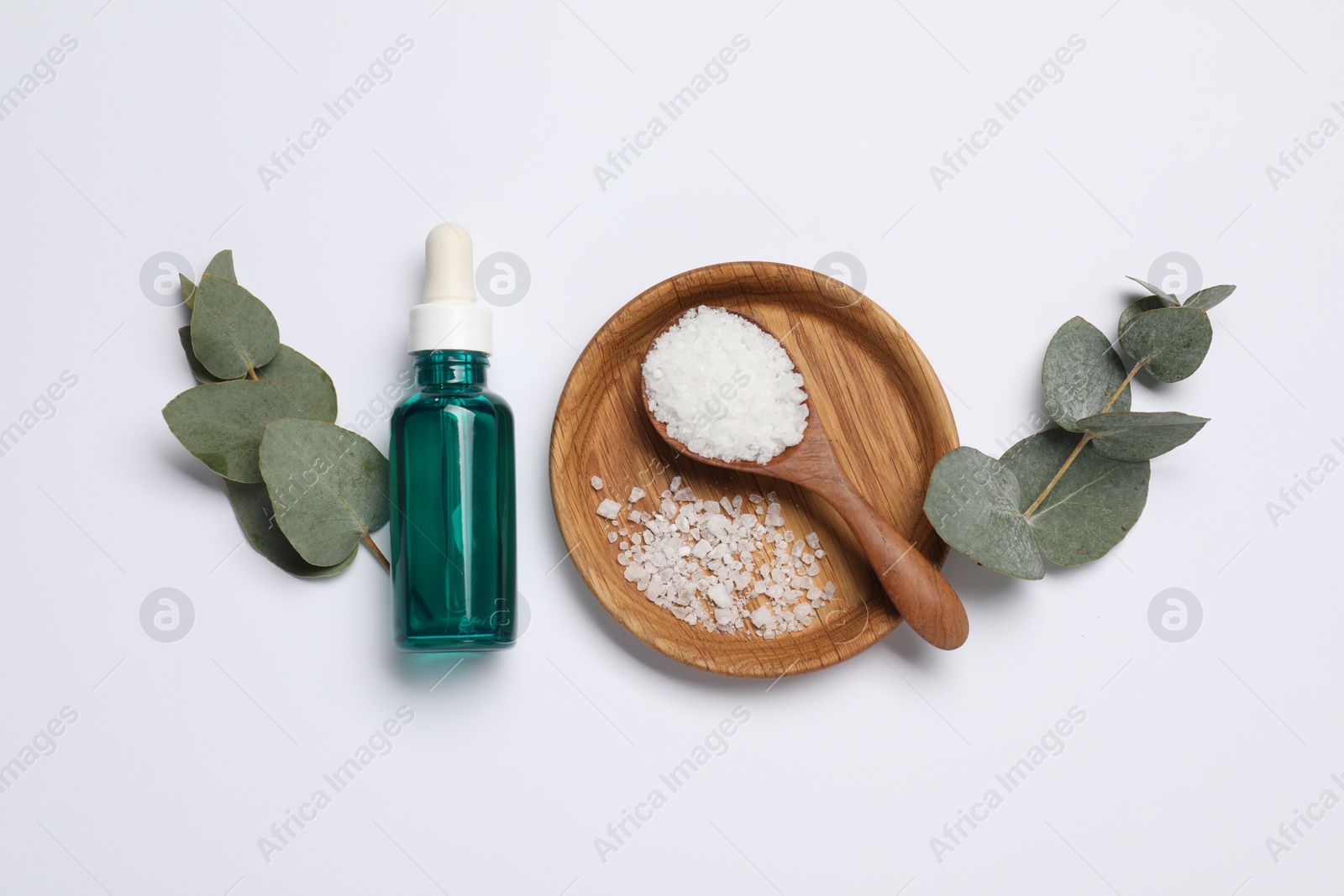 Photo of Aromatherapy products. Bottle of essential oil, sea salt and eucalyptus leaves on white background, flat lay