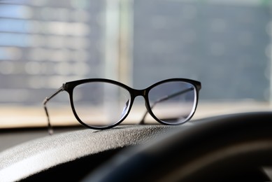 New stylish glasses on dashboard in car