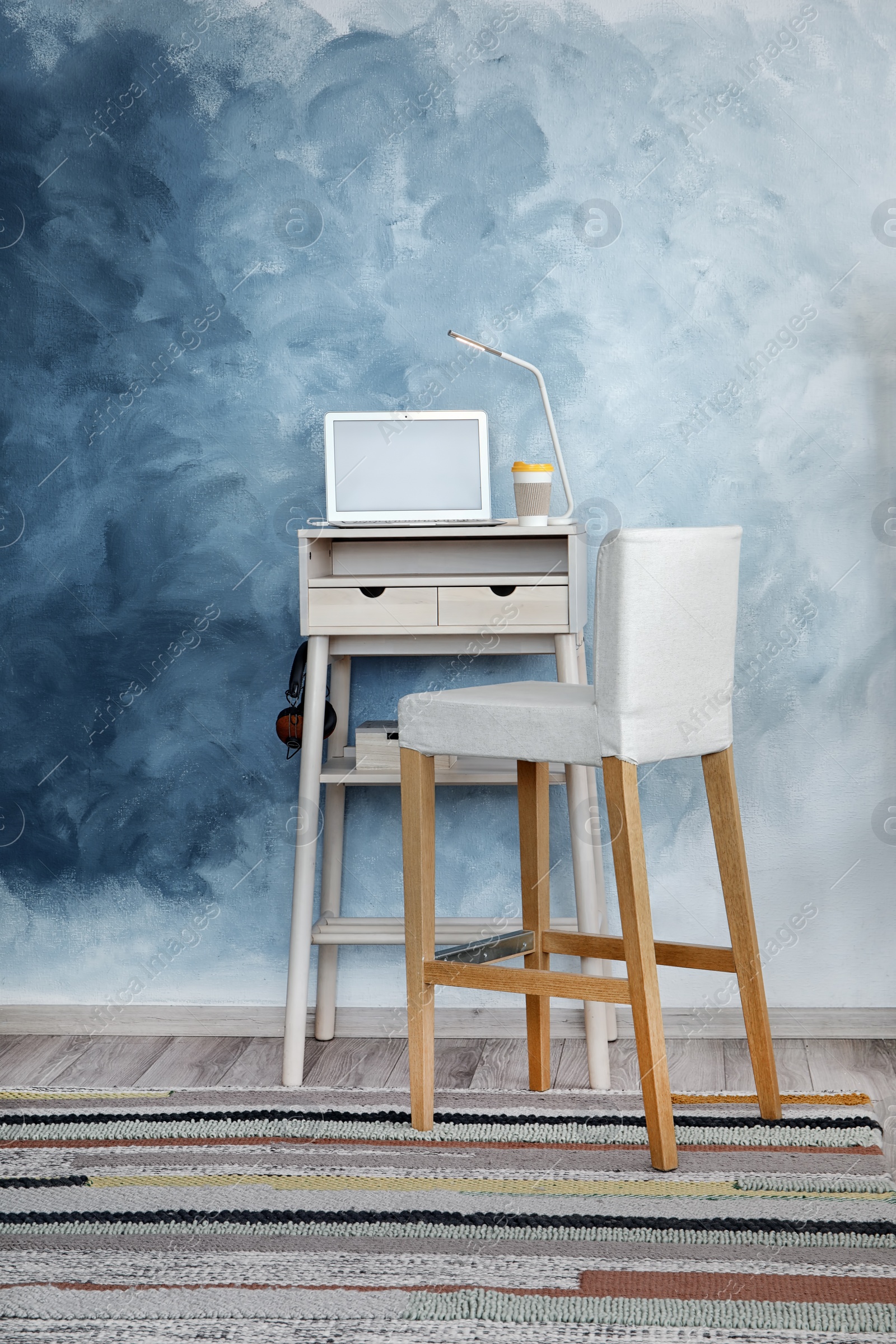 Photo of High wooden table with laptop as stand up workplace in modern interior