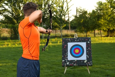 Man with bow and arrow aiming at archery target in park