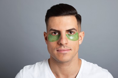 Photo of Man with green under eye patches on grey background