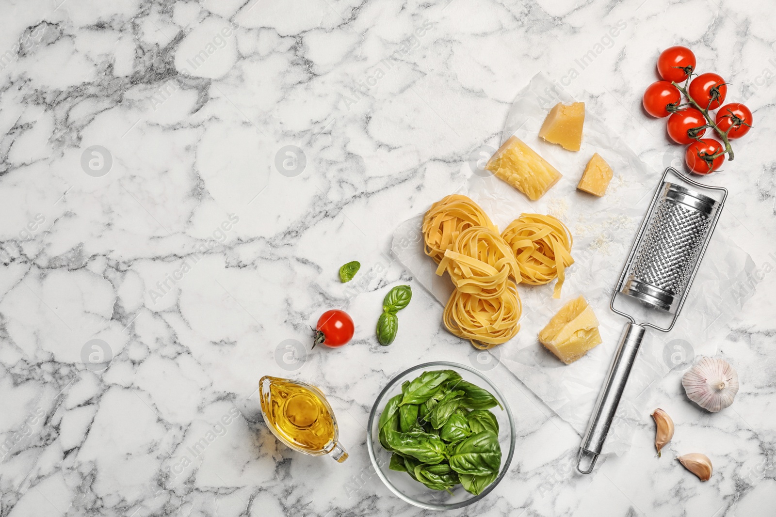 Photo of Beautiful composition with raw pasta and ingredients for sauce on marble background, top view