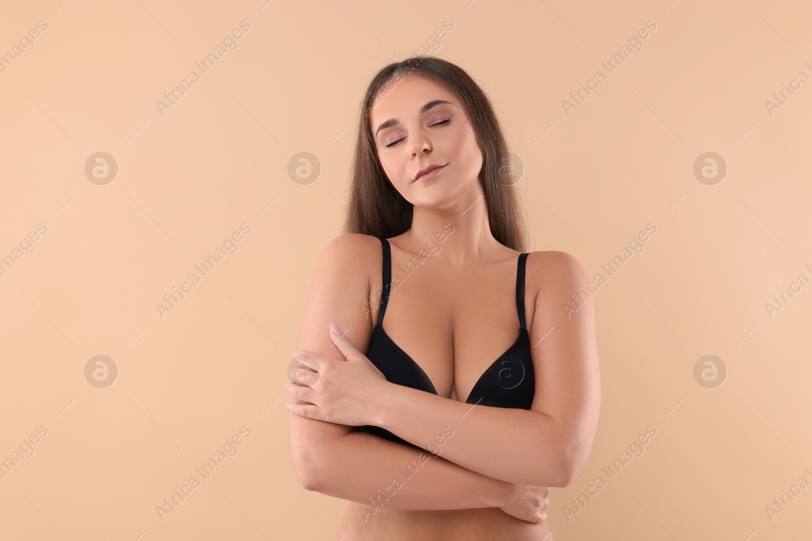 Photo of Portrait of young woman with beautiful breast on beige background