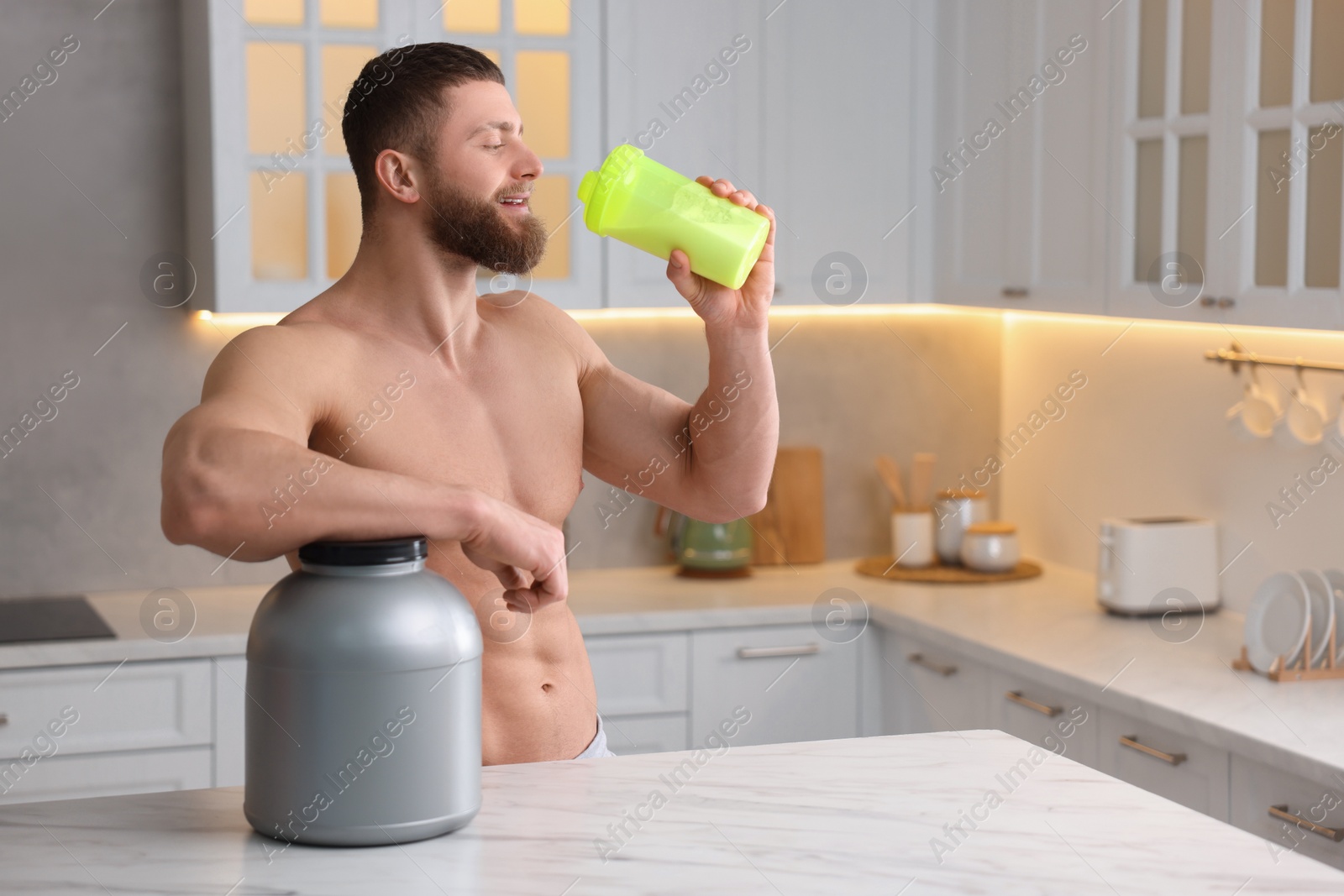 Photo of Young man with shaker of protein and powder at white marble table in kitchen, space for text