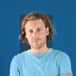 Facial recognition system. Young man with scanner frame and digital biometric grid on blue background