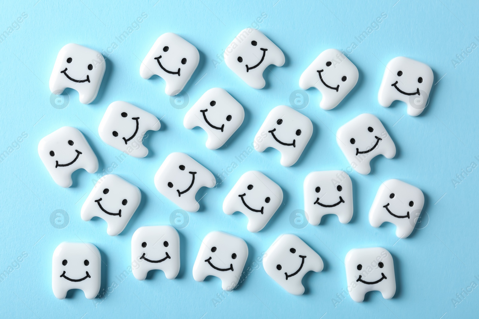 Photo of Many small plastic teeth with cute faces on color background, top view