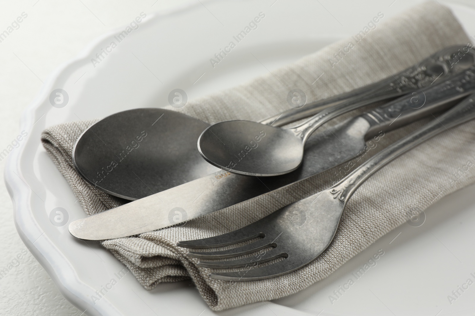 Photo of Stylish setting with cutlery, napkin and plate on table, closeup