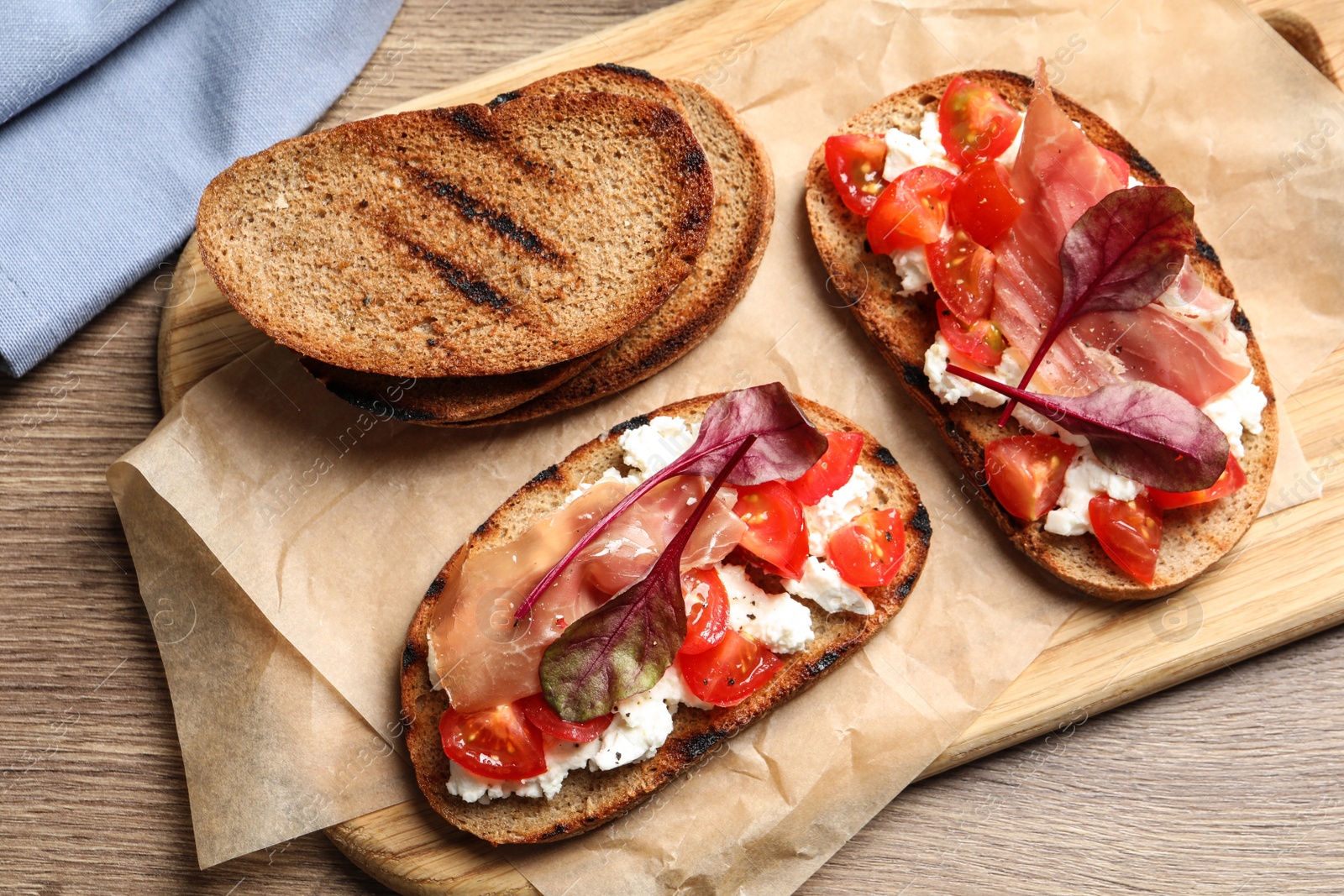 Photo of Board with tasty bruschettas on wooden table, top view