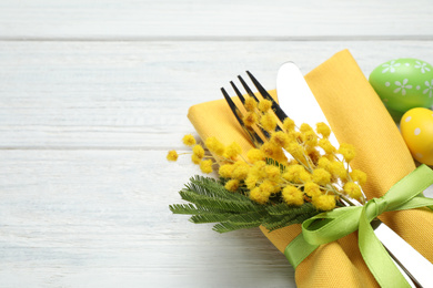 Closeup view of cutlery set with floral decor on wooden table, space for text. Easter celebration