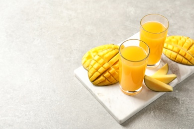 Fresh mango drink and cut fruits on table. Space for text