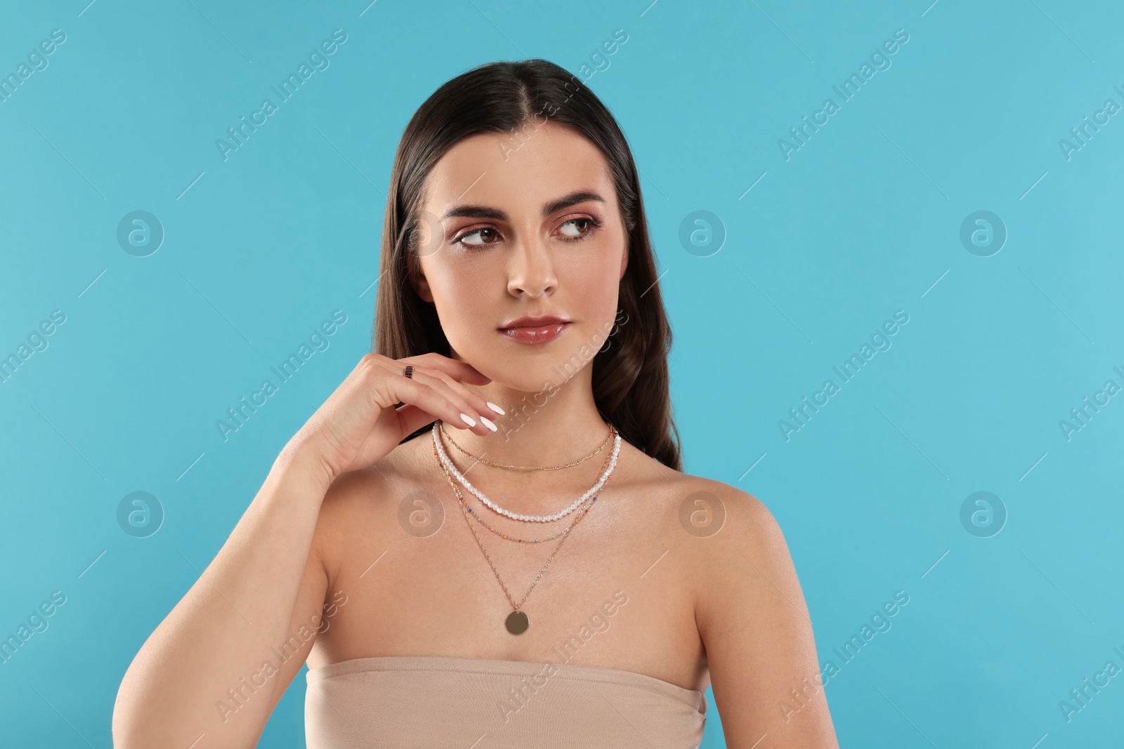 Photo of Beautiful woman with elegant jewelry on light blue background