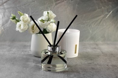 Photo of Reed diffuser, scented candle and eustoma flowers on gray marble table