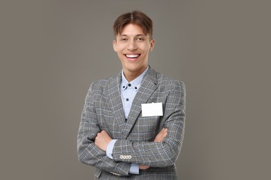 Happy man with blank badge on grey background