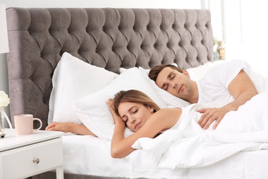 Photo of Young couple sleeping on soft pillows in bed at home