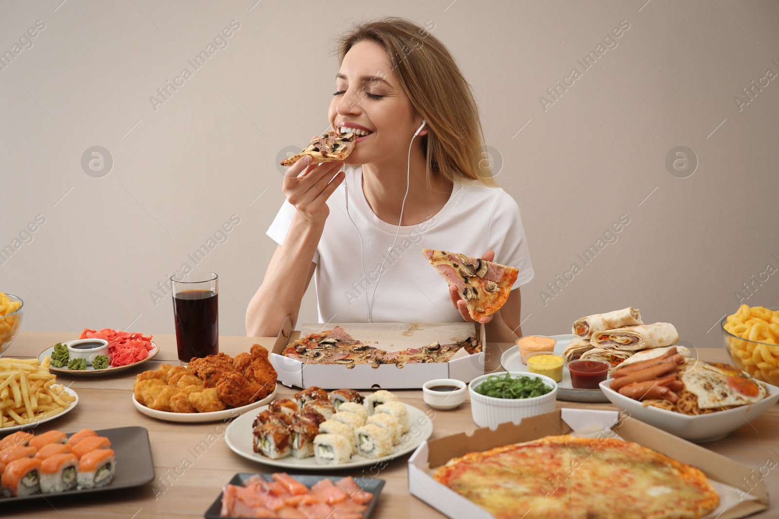 Photo of Food blogger eating at table against beige background. Mukbang vlog