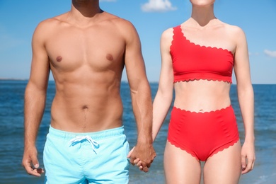 Woman in bikini and her boyfriend on beach, closeup. Lovely couple