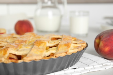 Photo of Delicious fresh peach pie on light kitchen table, closeup