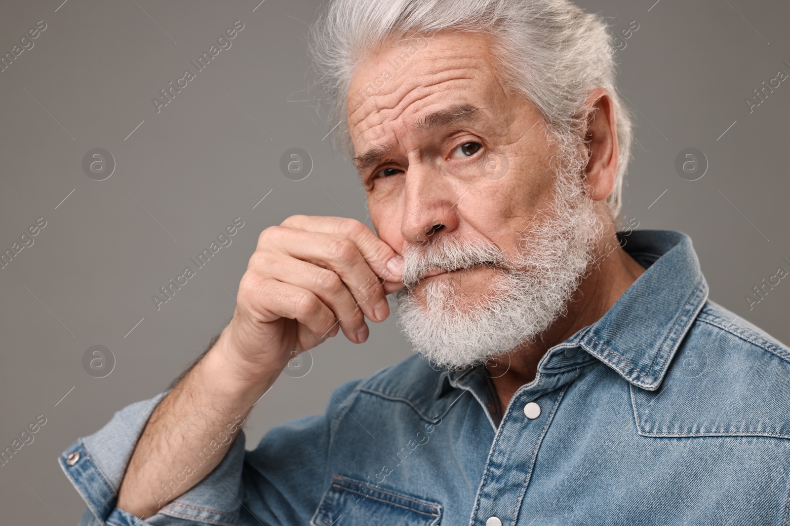 Photo of Senior man touching mustache on grey background