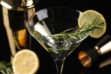 Photo of Martini cocktail with lemon slice and rosemary on table, closeup