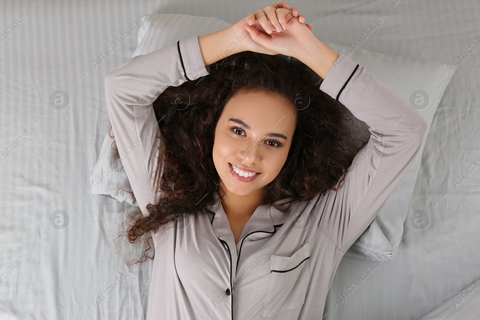 Photo of Beautiful African American woman lying in bed, top view