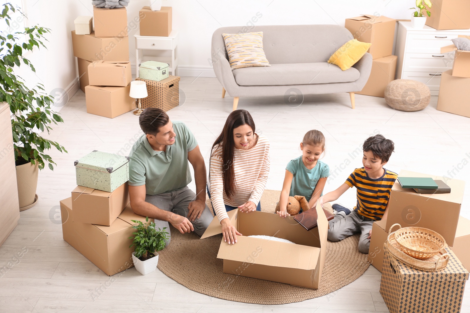 Photo of Happy family unpacking moving boxes at their new home