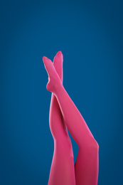 Photo of Woman wearing pink tights on blue background, closeup of legs