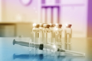 Image of Syringe and vials with medicine on table indoors