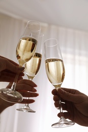 People clinking glasses with champagne at home, closeup