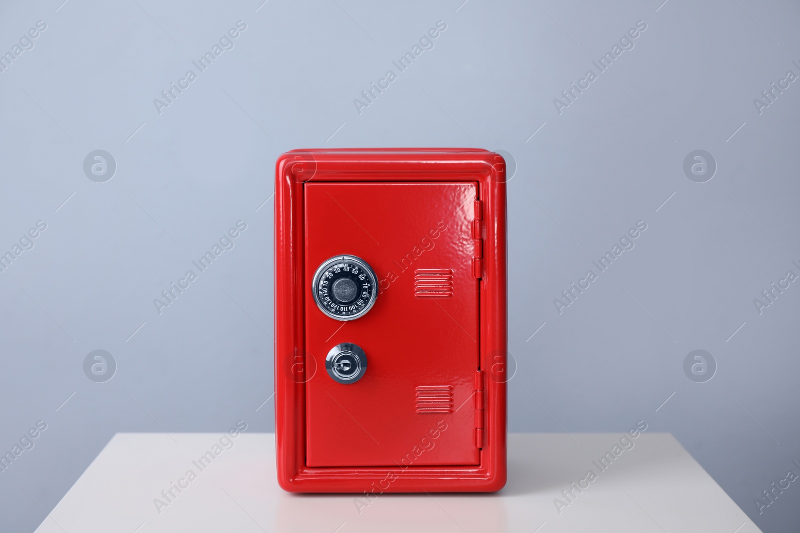 Photo of Red steel safe on white table against light grey background