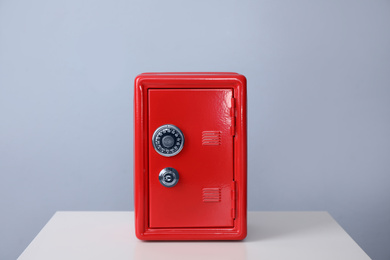 Photo of Red steel safe on white table against light grey background