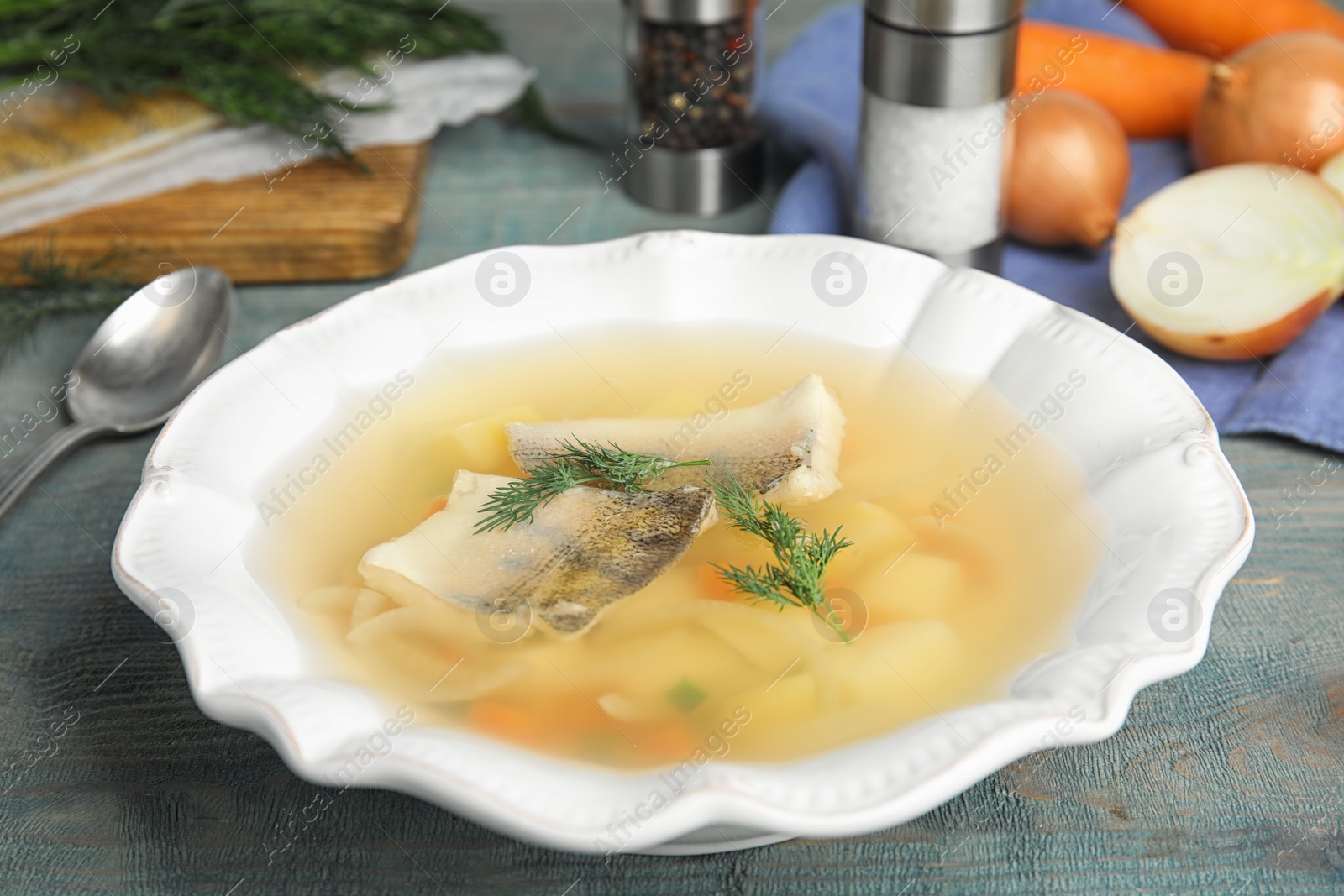 Photo of Delicious fish soup in bowl on blue wooden table