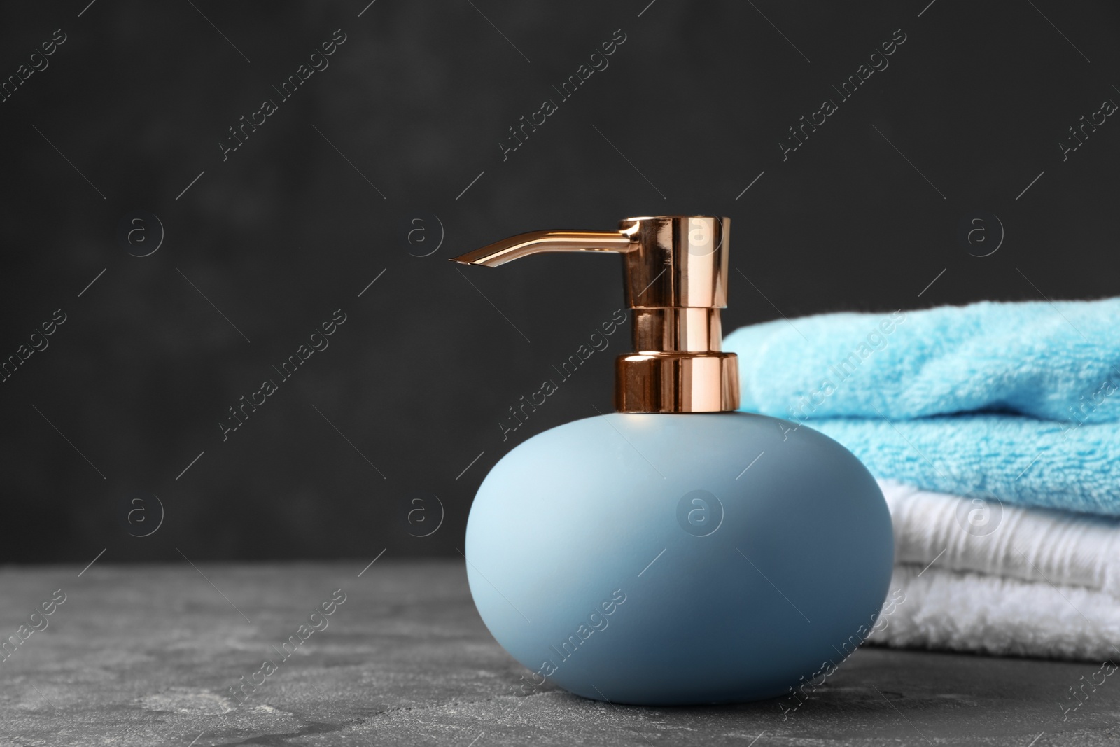 Photo of New stylish soap dispenser and towels on table. Space for text
