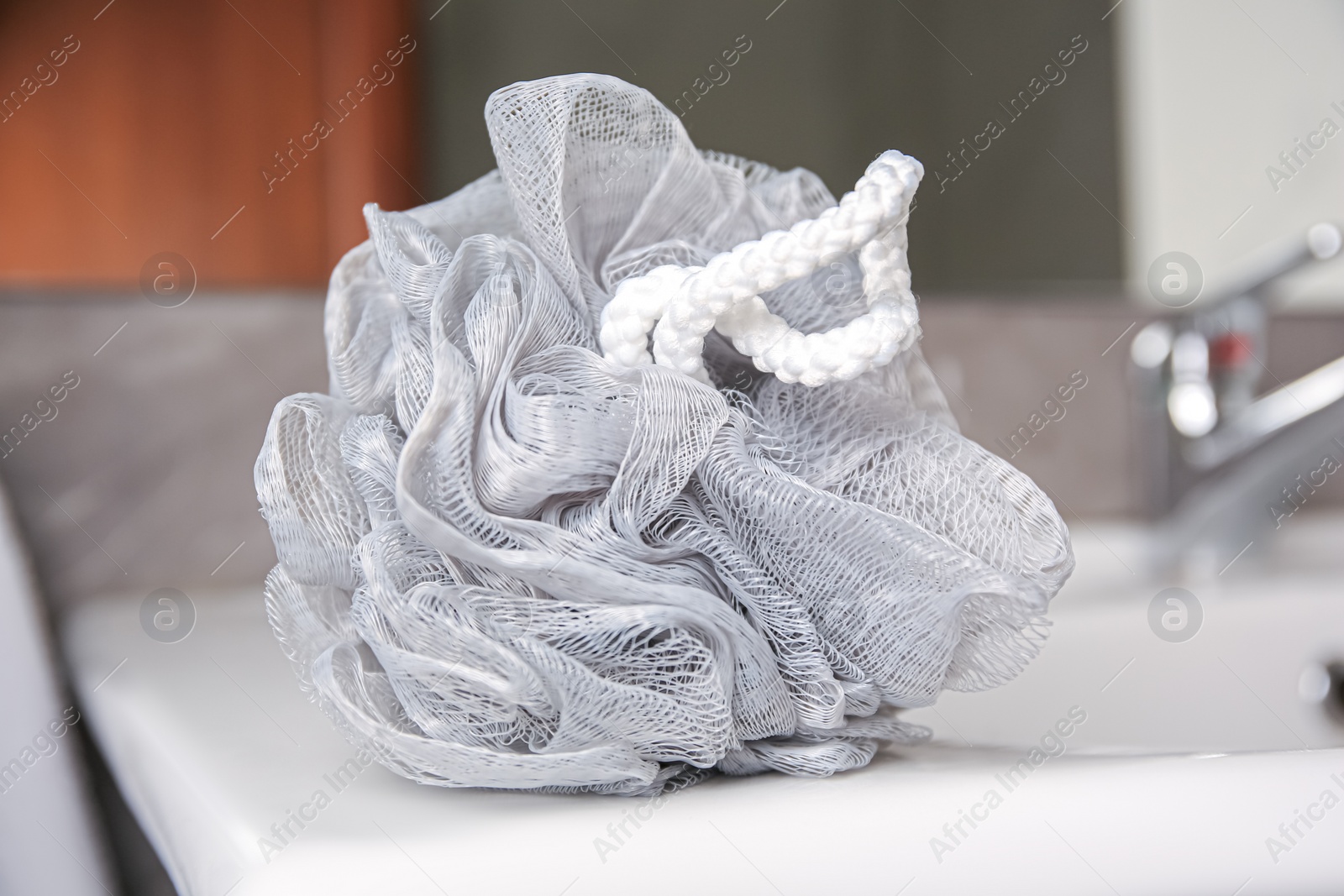 Photo of Grey shower puff on washbasin in bathroom, closeup