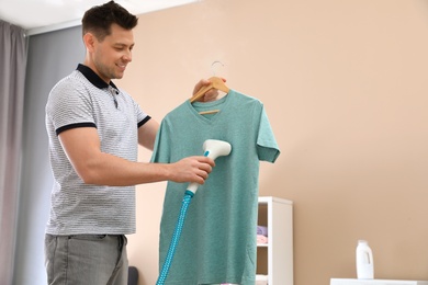 Man steaming his clothes in living room. Space for text