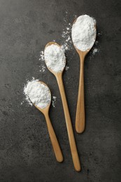 Photo of Baking powder in spoons on grey textured table, flat lay