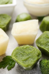 Photo of Frozen cauliflower and broccoli puree cubes on light grey table, closeup