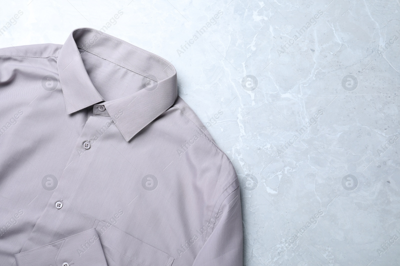 Photo of Stylish shirt on grey marble table, top view with space for text. Dry-cleaning service