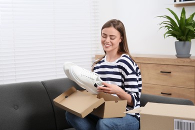 Photo of Happy woman with just unpacked new sneakers at home. Online store