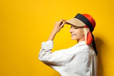 Photo of Beautiful young woman with bright dyed hair on orange background, space for text