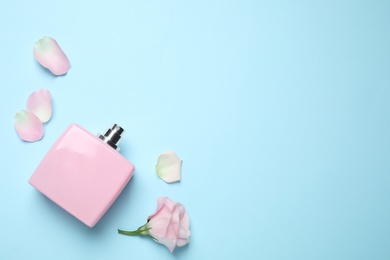 Photo of Flat lay composition with bottle of perfume and flower on light blue background, space for text