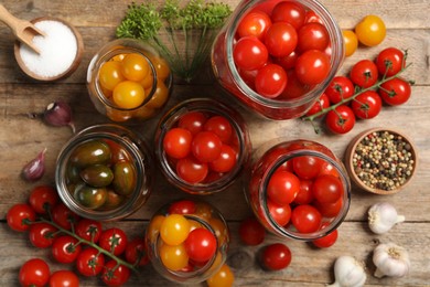 Photo of Pickling jars with fresh tomatoes on wooden table, flat lay