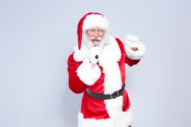 Photo of Santa Claus singing into microphone on color background. Christmas music