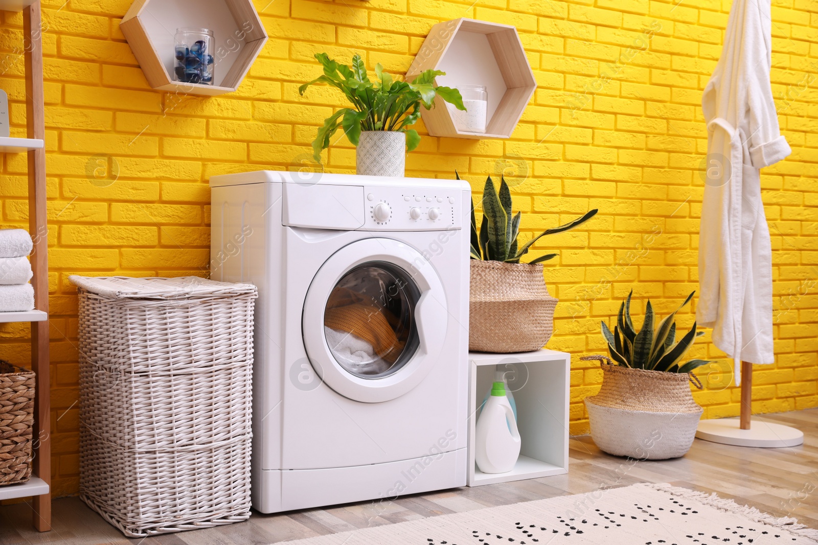 Photo of Laundry room interior with modern washing machine near yellow brick wall