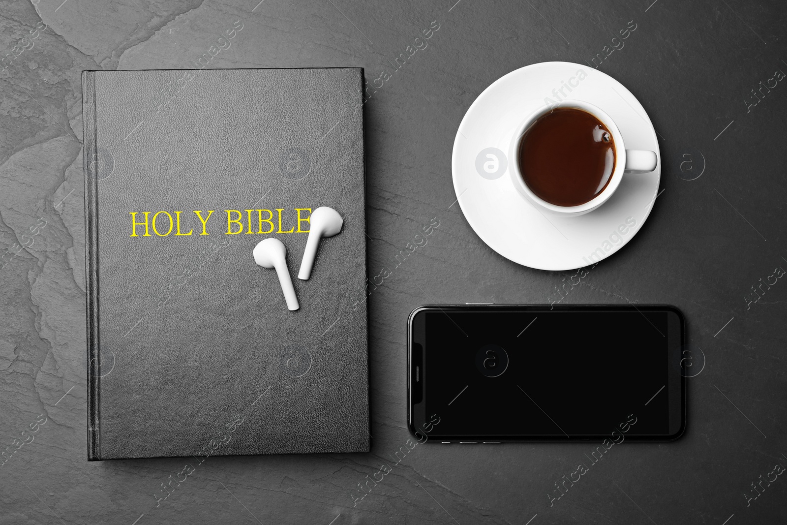 Photo of Bible, phone, cup of coffee and earphones on black background, flat lay. Religious audiobook