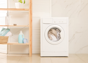 Modern washing machine with towels in bathroom