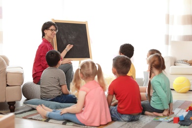 Photo of Young woman teaching little children indoors. Learning by playing