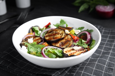 Photo of Delicious salad with roasted eggplant, cheese and arugula served on table
