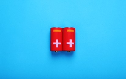 Photo of New C size batteries on light blue background, flat lay
