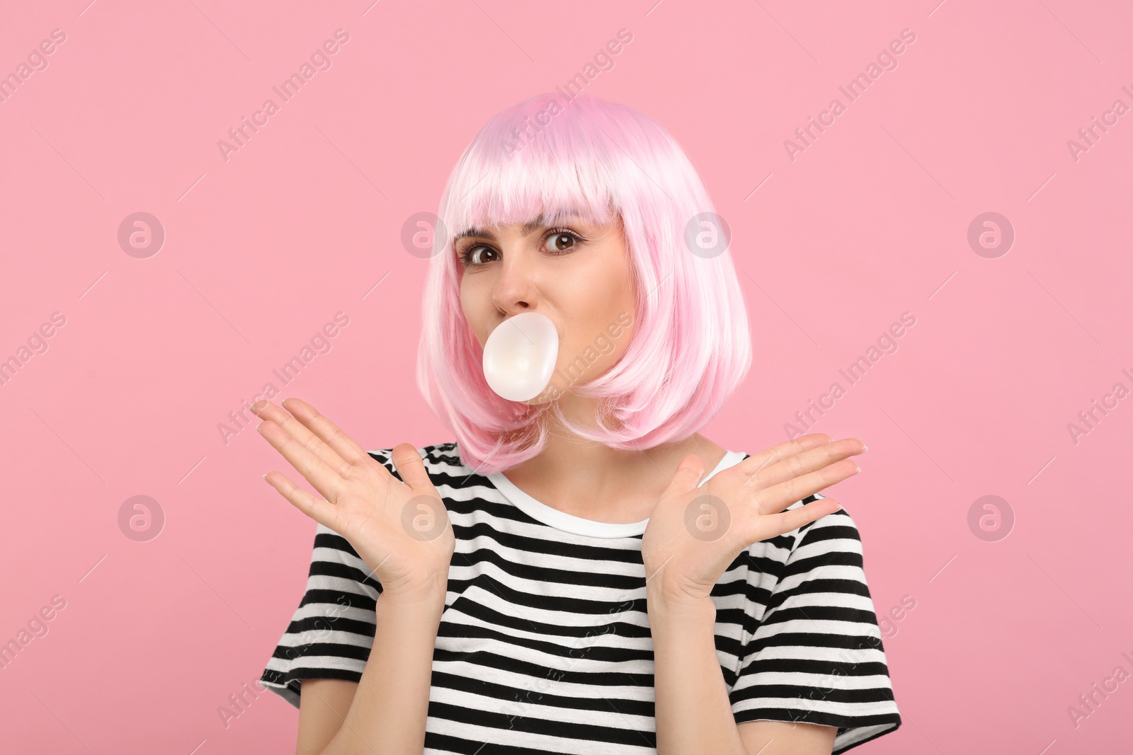 Photo of Beautiful woman blowing bubble gum on pink background