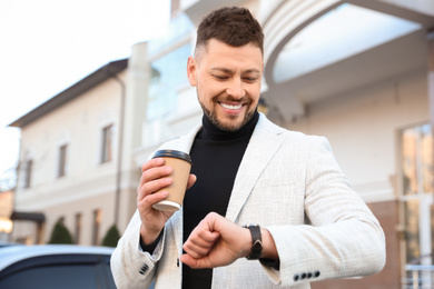 Businessman with cup of coffee on city street in morning